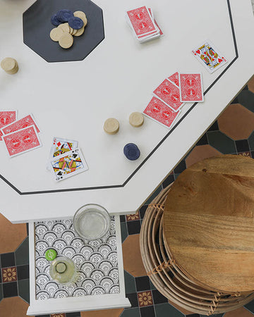 Game night setup with playing cards and dice on a white table against a patterned floor.